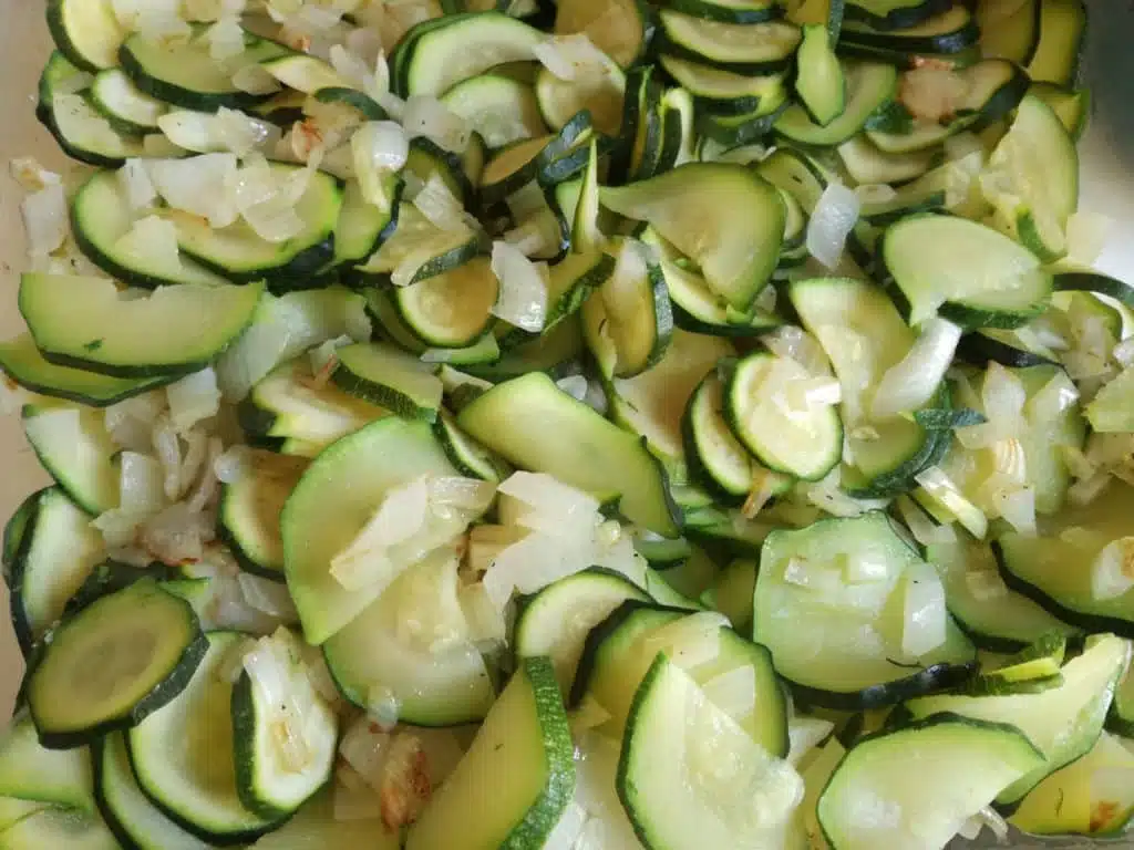 Recette du gratin de courgette : mélanger les courgettes avec les oignons